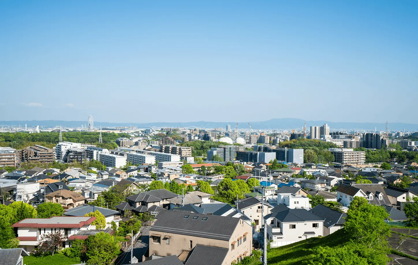 青空の下、住宅街と都市が広がる街並みの風景。賃貸物件エリア紹介や周辺環境の説明をイメージした写真。