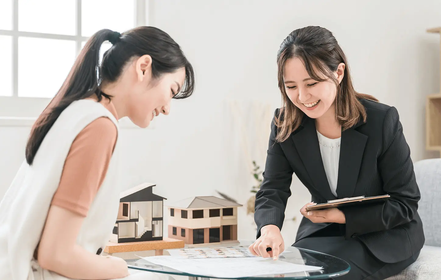 女性スタッフが間取り図を指しながら、来訪者に賃貸物件についてわかりやすく説明している相談風景。安心して相談できる接客をイメージした写真。